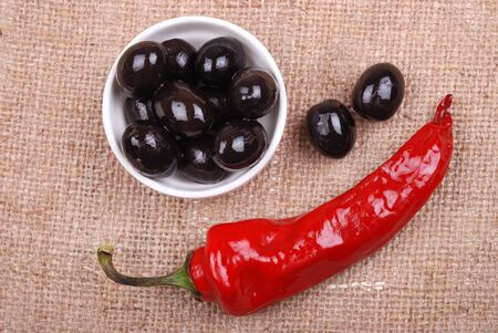 Red hot chili pepper and olives on a rough sackclothの写真素材