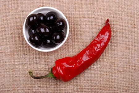 Red hot chili pepper and olives on a rough sackclothの写真素材