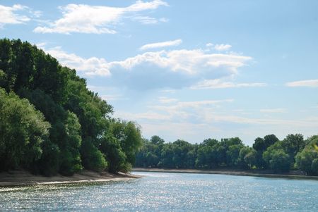 Summer landscape. River, riverside and trees on blue sky backgroundの写真素材