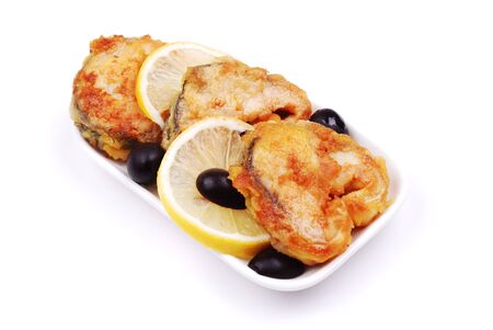 Fried fish with a lemon and olives on whiteの写真素材
