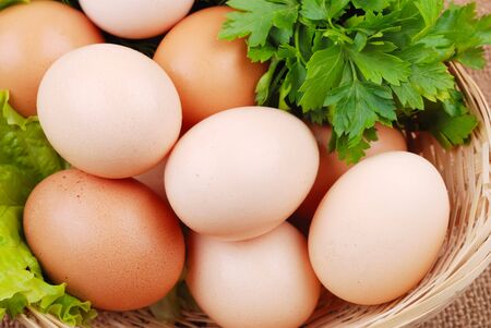 Basket with eggs on sackcloth with greensの写真素材