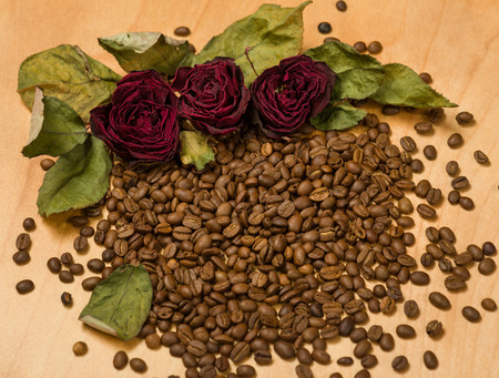 dry red roses on coffee seeds and wooden backgroundの写真素材