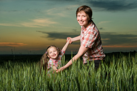 happy mother and child in green field at sunsetの写真素材