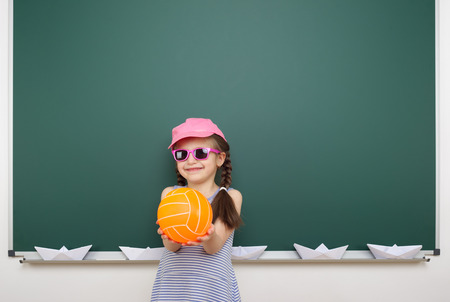 Schoolgirl with ball near the school boardの写真素材
