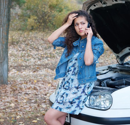 Woman with broken car talk on phone with hood up