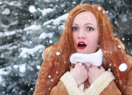 Surprised  redhead woman winter outdoor portrait, snowy fir trees backgroundの写真素材