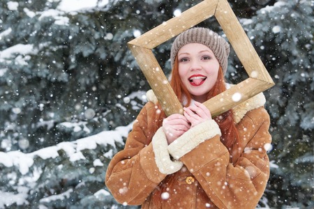 Woman outdoor portrait in wooden photo frame at winter season