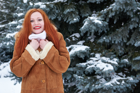 Winter redhead woman outdoor portrait, snowy fir trees backgroundの写真素材