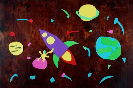 Spaceship in space. Applique made by child from paper on wood.の写真素材