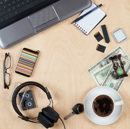 Flat lay of personal stuff, notebook computer,cards, coffee, money and other. Flat design and top view on desk as frame with blank center on wood background.の写真素材