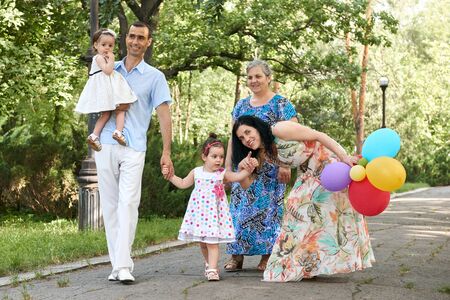 big family walk in summer city park, parents with child and grandmother, summer season, green grass...