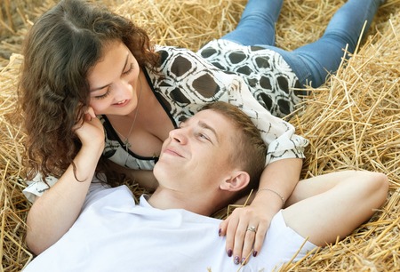 happy young couple lie in straw, wheaten field at evening, romantic people concept, beautiful landscape, summer seasonの写真素材
