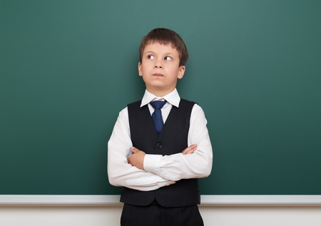 school student boy posing and think at the clean blackboard, grimacing and emotions, dressed in a...