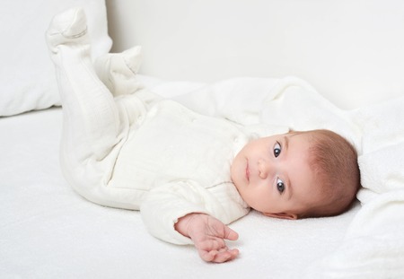 baby on white towel in bed