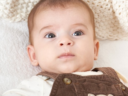 baby portrait lie on white towel in bed, yellow toned