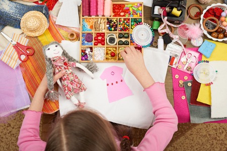 girl sews doll clothes, top view, sewing accessories top view, seamstress workplace, many object for...