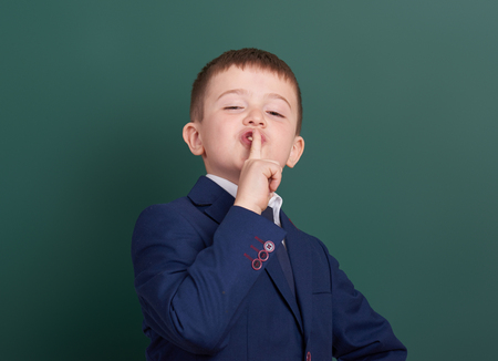 school boy point the finger near blank chalkboard background, dressed in classic black suit, group pupil, education conceptの写真素材