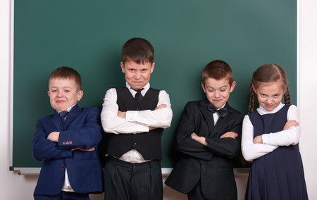 group pupil as a gang, posing near blank chalkboard background, grimacing and emotions, dressed in classic black suitの写真素材