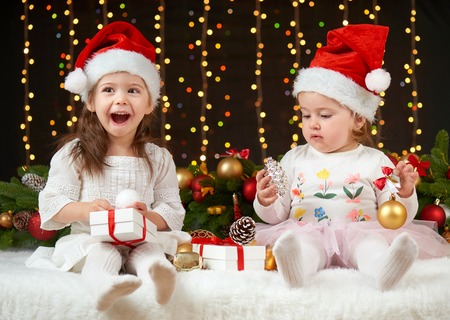 child girl portrait in christmas decoration, happy emotions, winter holiday concept, dark background with illumination and boke lightsの写真素材