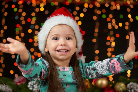 child girl portrait in christmas decoration, happy emotions, winter holiday concept, dark background with illumination and boke lightsの写真素材