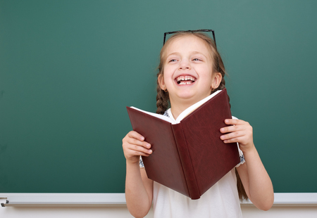 School girl read book, posing at school board, empty space, education conceptの写真素材