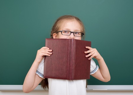 School girl read book, posing at school board, empty space, education conceptの写真素材