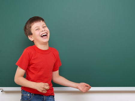 Schoolboy play and laugh near a blackboard, empty space, education conceptの写真素材