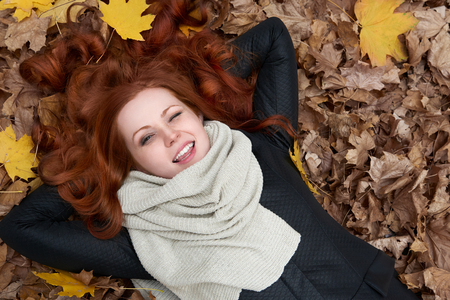 girl lie on autumn leaves background in city parkの写真素材