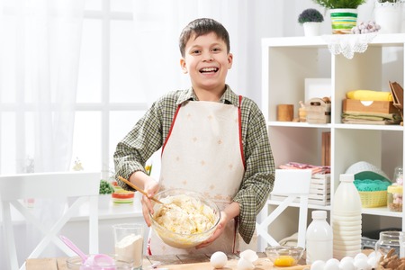 Boy cooking at home, making dough, buns and cookiesの写真素材