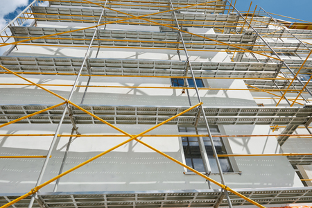 scaffolding near a new house, building exterior, construction and repair industry, white wall and window, yellow pipeの写真素材
