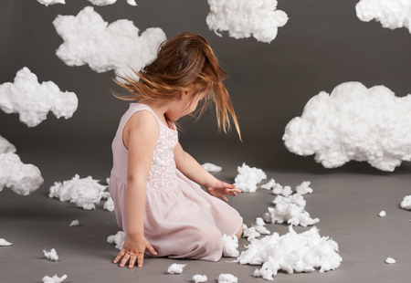 girl playing with clouds, shot in the studio on a gray backgroundの写真素材