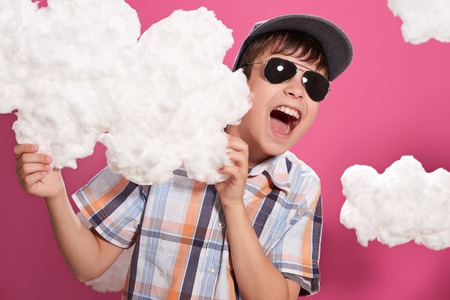 fashionable boy posing on a pink background with cloudsの写真素材