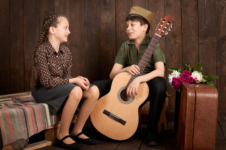 children are dressed in retro military uniforms sending a soldier to the army, dark wood background, retro styleの写真素材