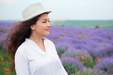 young woman is in the lavender field, beautiful summer landscape with red poppy flowersの写真素材