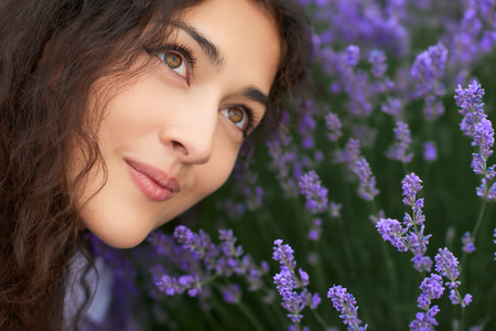 young woman is in the lavender field, beautiful portrait, face closeup, summer landscape with red poppy flowersの写真素材