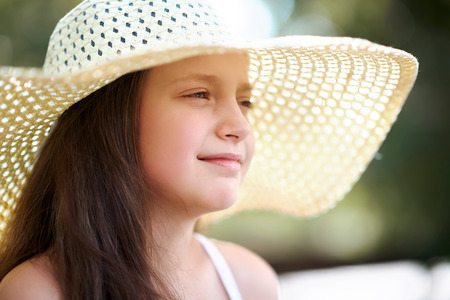 portrait of a little girl wearing a big hat, beautiful sunny day, bright sun and shadows, face...