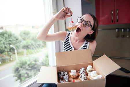 girl eating tasty cakes, sitting by the window, sweet food and pleasureの写真素材