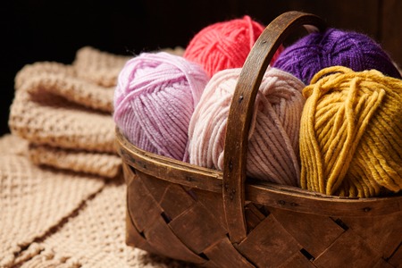 Colorful wool threads for knitting in basket, wooden backgroundの写真素材