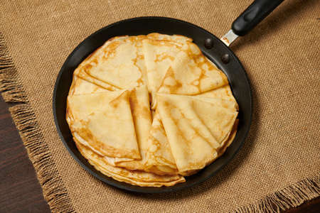 Crepe closeup, thin pancake on a frying pan, wood backgroundの写真素材