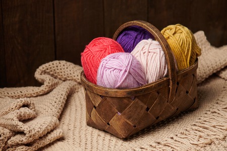 Colorful wool threads for knitting in basket, wooden backgroundの写真素材