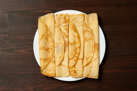 Crepe closeup, heap of thin pancakes on a dish, wood backgroundの写真素材