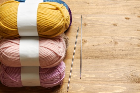 colorful wool threads for knitting on wooden background