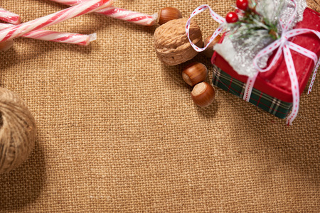 Christmas decoration background, fir tree, textile, beads, gifts, old paper, nuts and other stuff on sackcloth. Empty space for text, new year theme.の写真素材