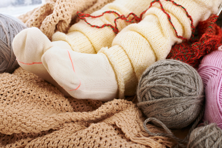 Child legs in warm socks are on a window sill with wool yarns.の写真素材