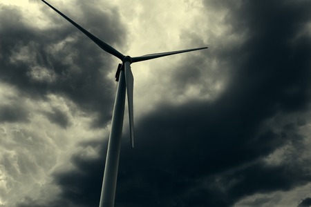 The wind generator is in dark stormy sky.の写真素材