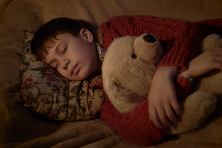 boy sleep in bed with bear toyの写真素材