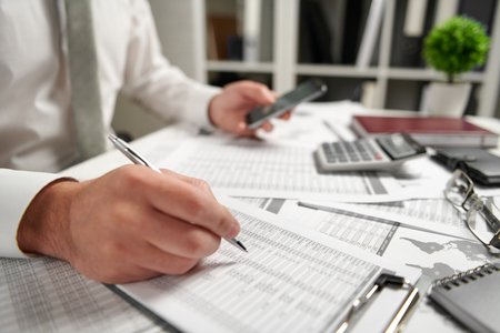 Businessman working at office and calculating finance, reads and writes reports. Business financial accounting concept.の写真素材