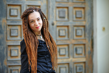 dreadlocks fashionable girl posing at old wooden door background