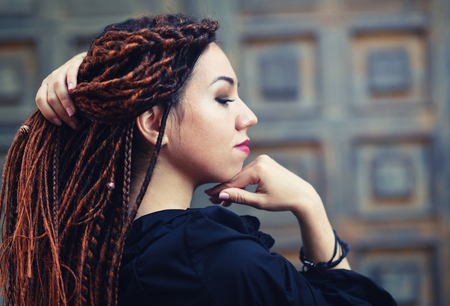 dreadlocks closeup, fashionable girl posing at old wooden door backgroundの写真素材