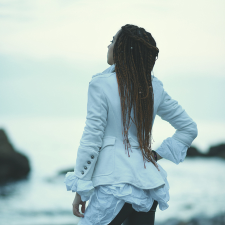 dreadlocks fashionable girl posing near sea at sunsetの写真素材